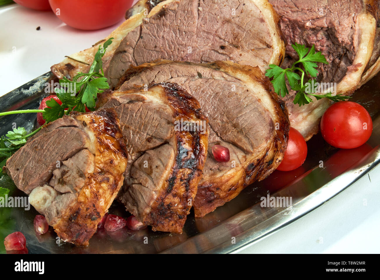 A piece of baked red meat sliced on an oval plate. Beautiful serving ...