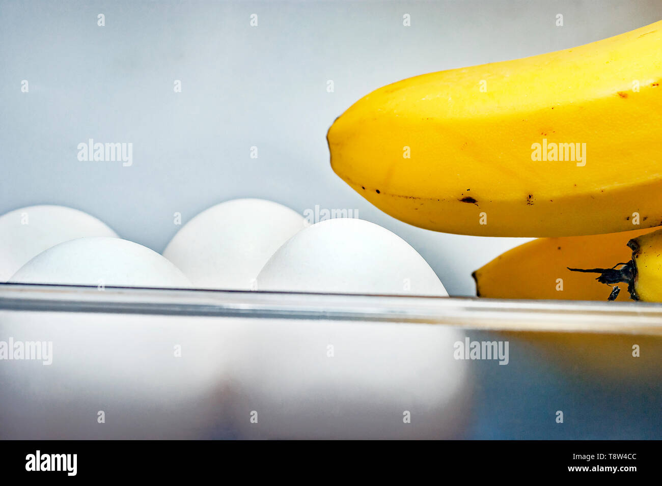 Banana Fingers and Four White Eggs in Open Refrigerator Door Plastic