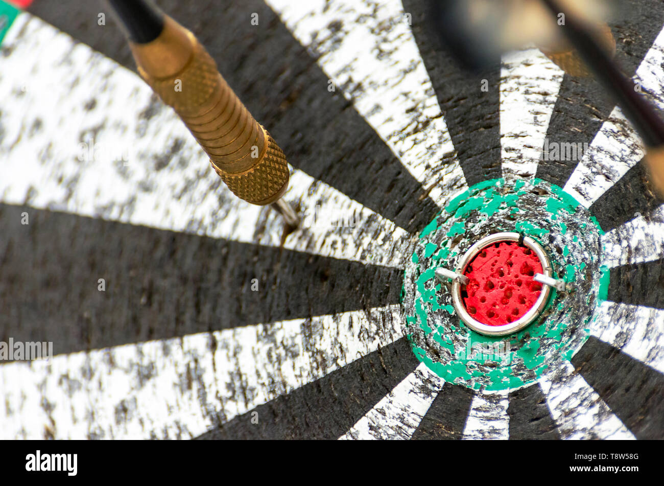 Darts Missing Bullseye on a Worn Out Dartboard. Proper Targeting, Losing Concept. Stock Photo