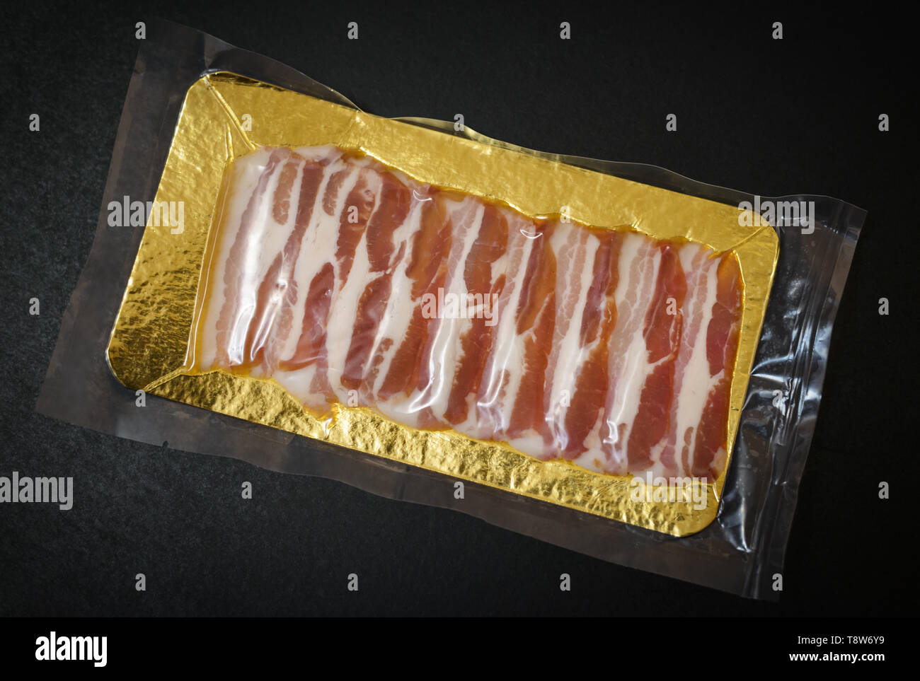Bacon in the package on dark background. Stock Photo