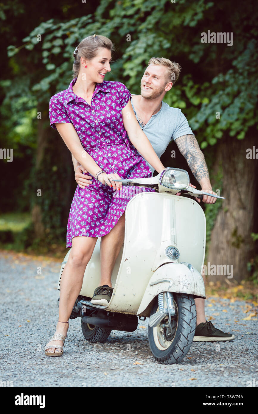 Young woman sitting on her boyfriend's lap sitting on scooter Stock Photo -  Alamy