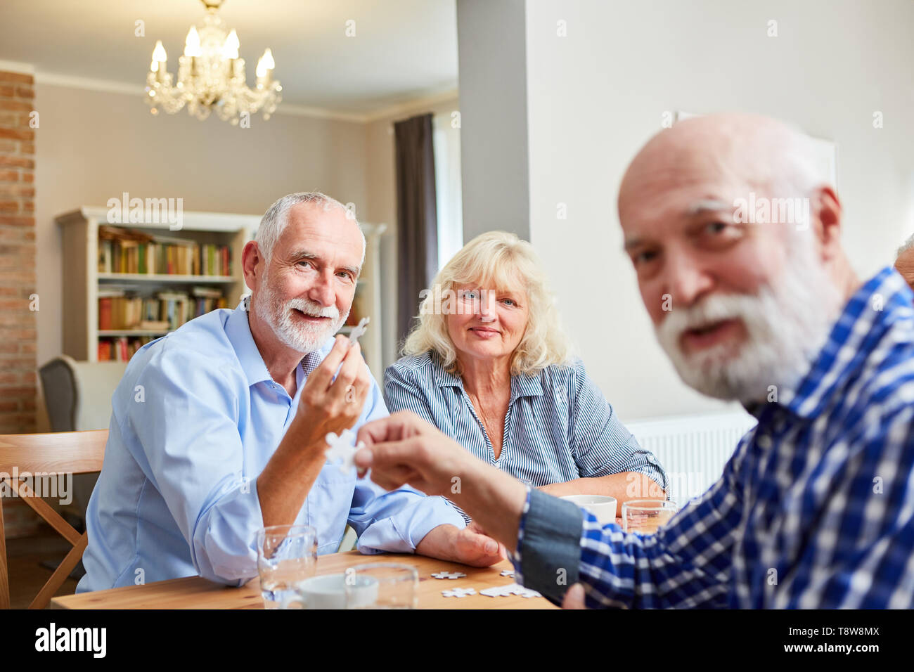 Group of seniors playing puzzle together in retirement home or apartment Stock Photo