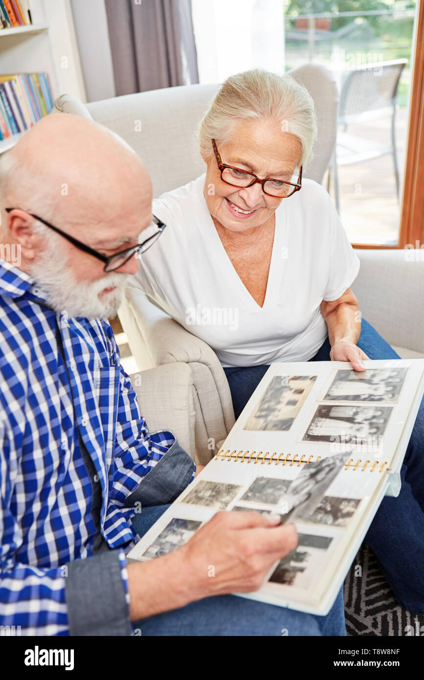 Happy seniors couple is looking at old family photos in photo album indoors Stock Photo