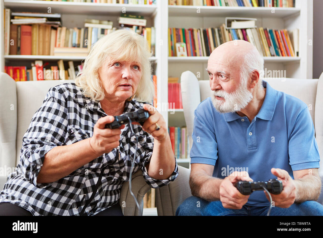 Senior couple as vital retiree at video game console in the living room Stock Photo