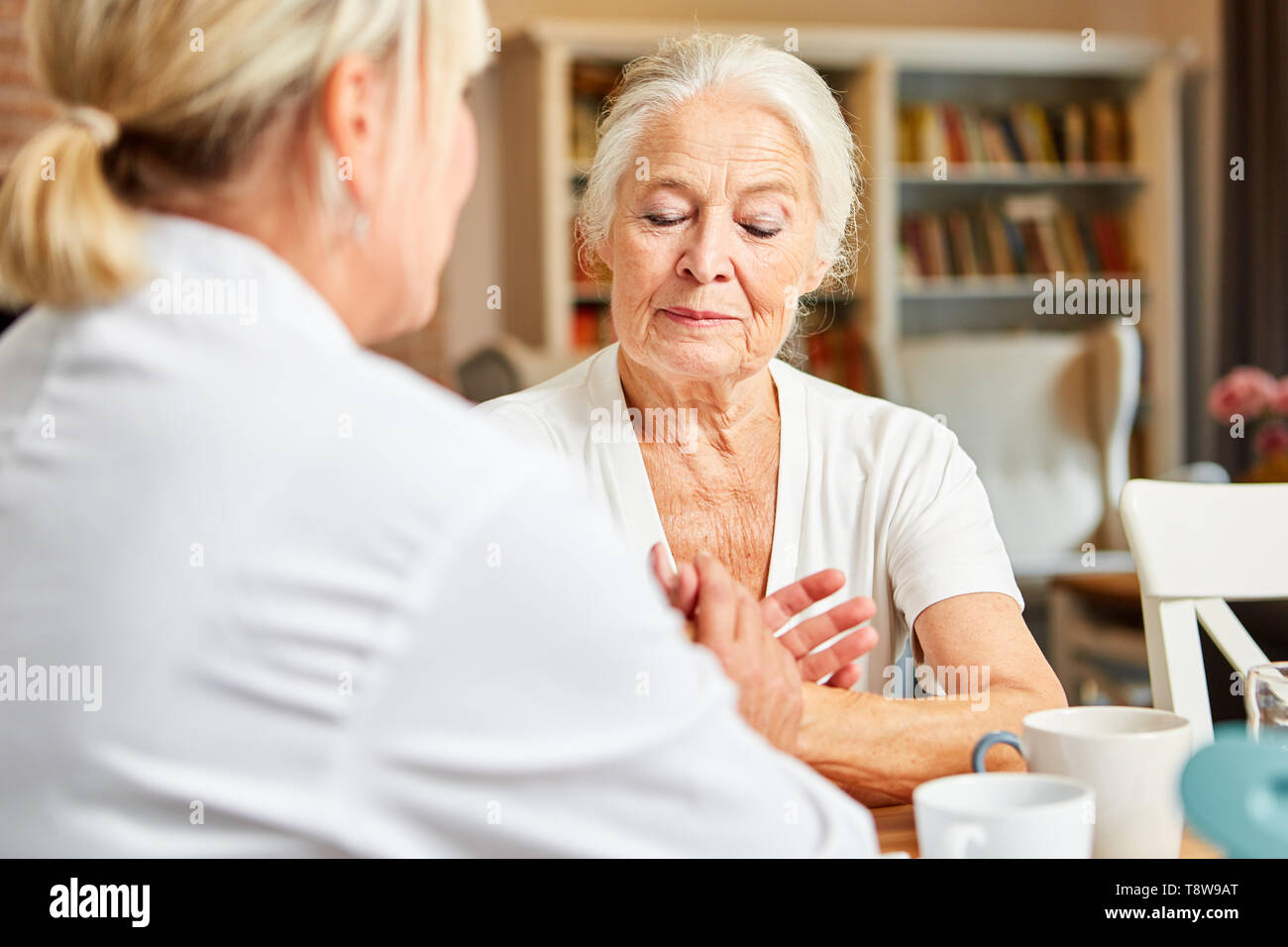 Woman of the nursing service consoles sad senior citizen in the nursing home Stock Photo