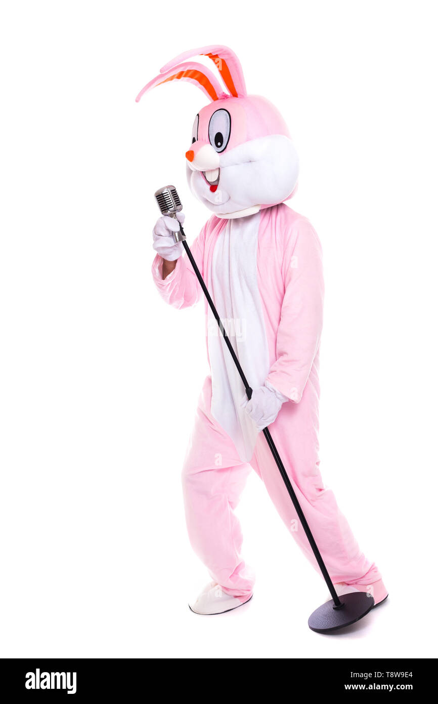 Life size rabbit costume or easter bunny sings in retro microphone. Funny musician singer have fun with Elvis microphone Stock Photo