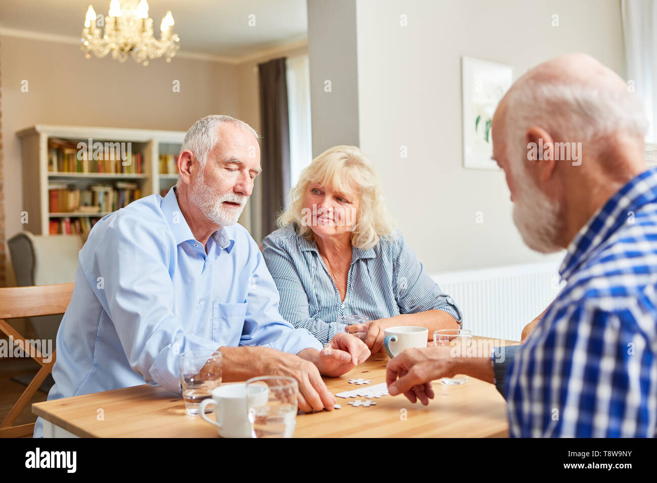 Group of seniors playing puzzle as memory training in retirement home Stock Photo