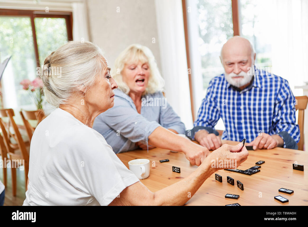 Group of seniors in retirement home playing dominoes as a leisure