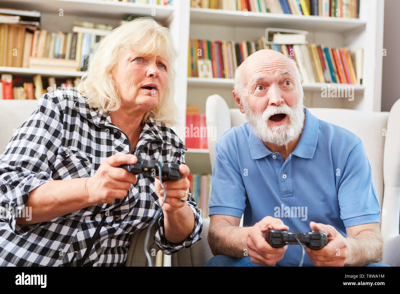 Senior couple in video game competition against each other full of excitement Stock Photo