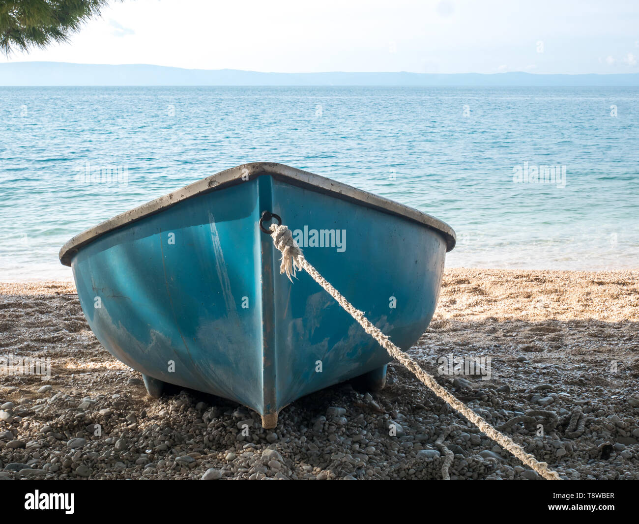 Blue boat with rope on the beach close to the blue sea background Stock Photo