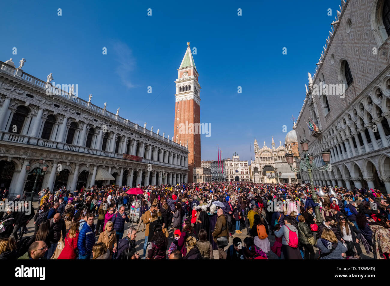 Thousands of people are gathering at San Marco Square, Piazza San Marco to celebrate the Venetian Carnival, St Mark's Campanile, Campanile di San Marc Stock Photo