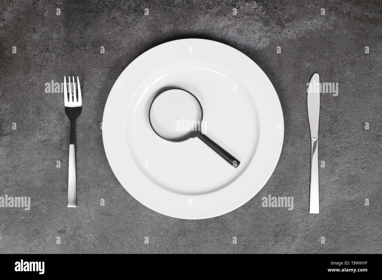 Healthy eating concept. Empty plate, cutlery and magnifying glass Stock Photo
