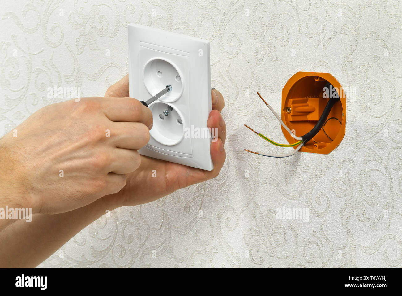 hands of an electrician connect the power outlet to the mains Stock