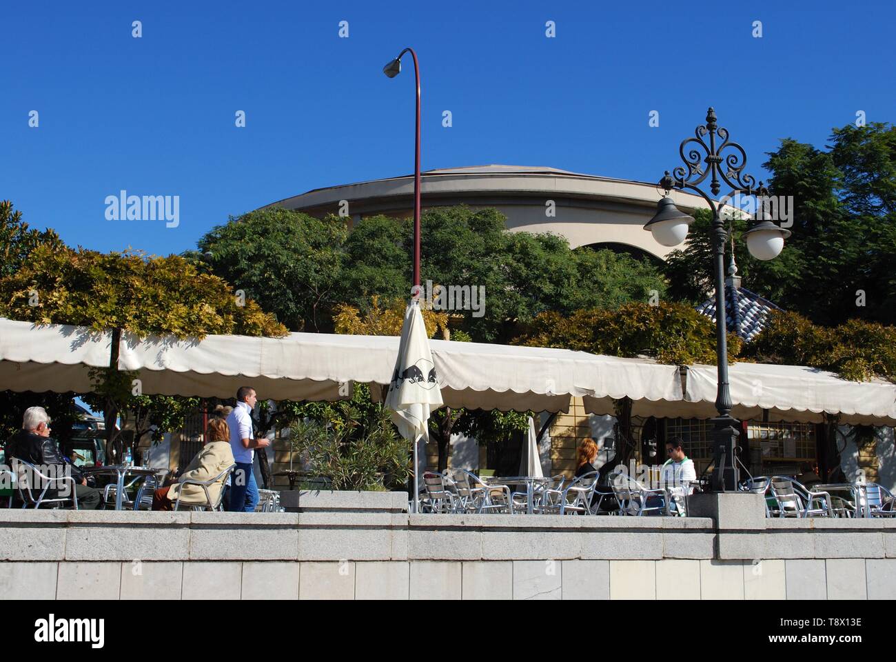 People relaxing at pavement cafes with the Maestranza theatre to the rear, Seville, Seville Province, Andalusia, Spain. Stock Photo