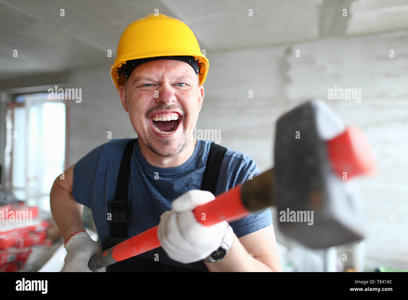 Angry builder holding sledgehammer and Stock Photo