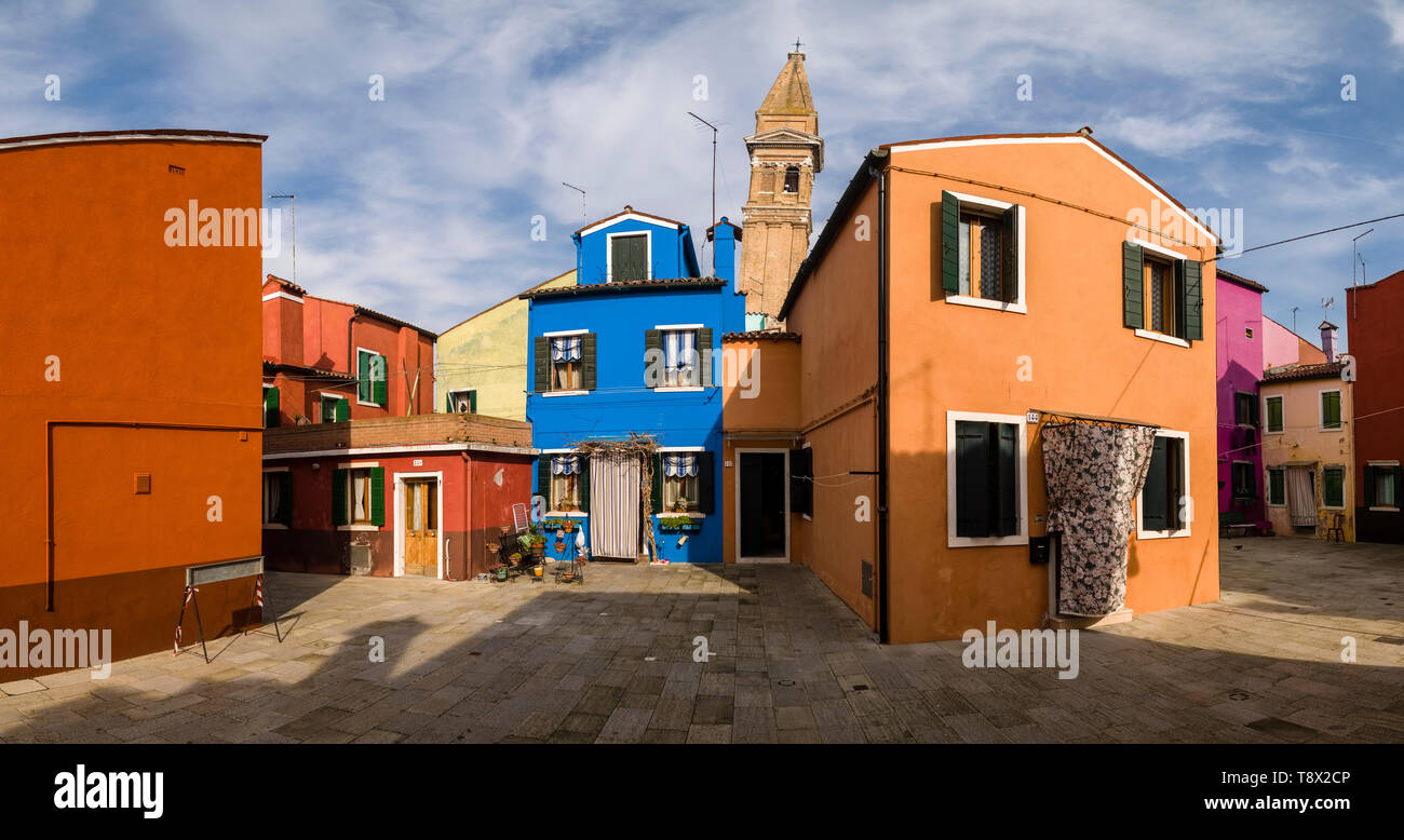 Colorfully painted houses on the island Burano, the leaning tower of the St Martino Church, Chiesa di San Martino, in the distance Stock Photo