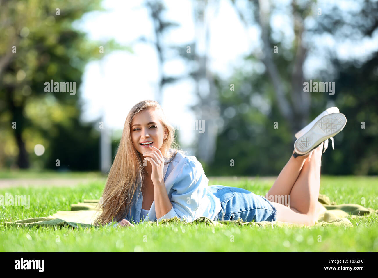 Beautiful young woman lying on green grass outdoors Stock Photo - Alamy