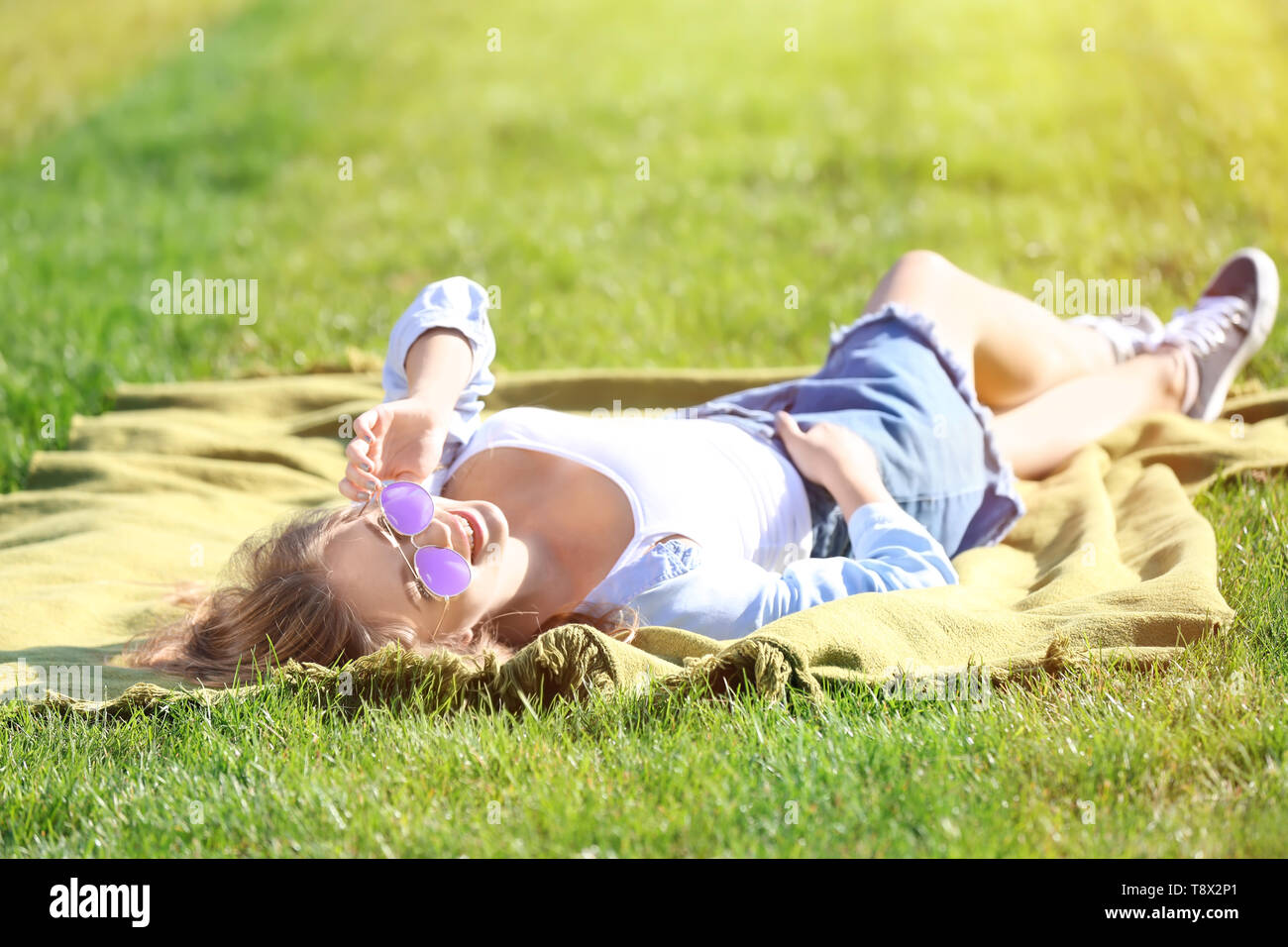 Beautiful young woman lying on green grass outdoors Stock Photo - Alamy