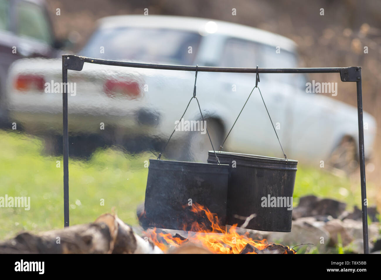 Heating up water in the metal buckets using a bonfire. Buckets hanging