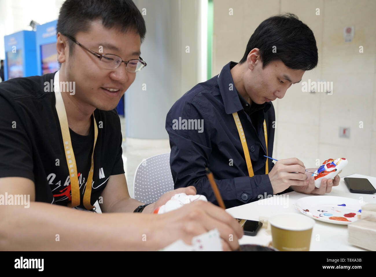 Beijing, China. 15th May, 2019. People paint clay sculptures at the intangible cultural heritage interactive area of the media center of the Conference on Dialogue of Asian Civilizations (CDAC) in the China National Convention Center in Beijing, capital of China, May 15, 2019. The opening ceremony of the CDAC was held here Wednesday. Credit: Shen Bohan/Xinhua/Alamy Live News Stock Photo