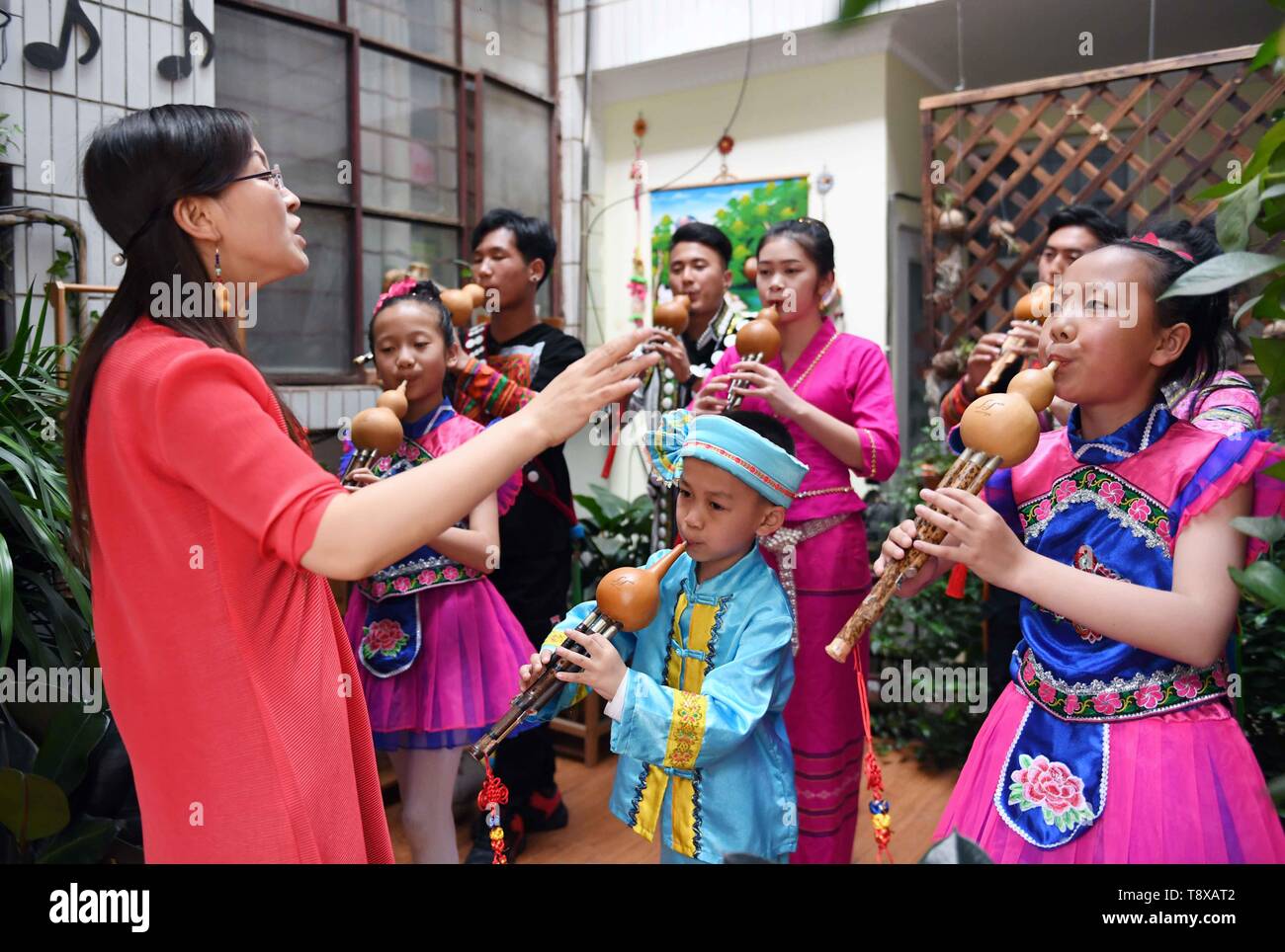 (190515) -- QUJING, May 15, 2019 (Xinhua) -- Teacher Yang Huanyu directs students to play the Hulusi at an art school at Qujing, southwest China's Yunnan Province, May 11, 2019. Hulusi is a free-reed wind instrument from China. It is made of a gourd with three bamboo pipes inserted into the bottom end of the gourd wind chest. The bamboo pipes consist of one main pipe which has finger holes for making different tones and two drone pipes which can play chord. It is mainly used by minority ethnic groups in Yunnan province and it has a clarinet-like sound. (Xinhua/Yang Zongyou) Stock Photo