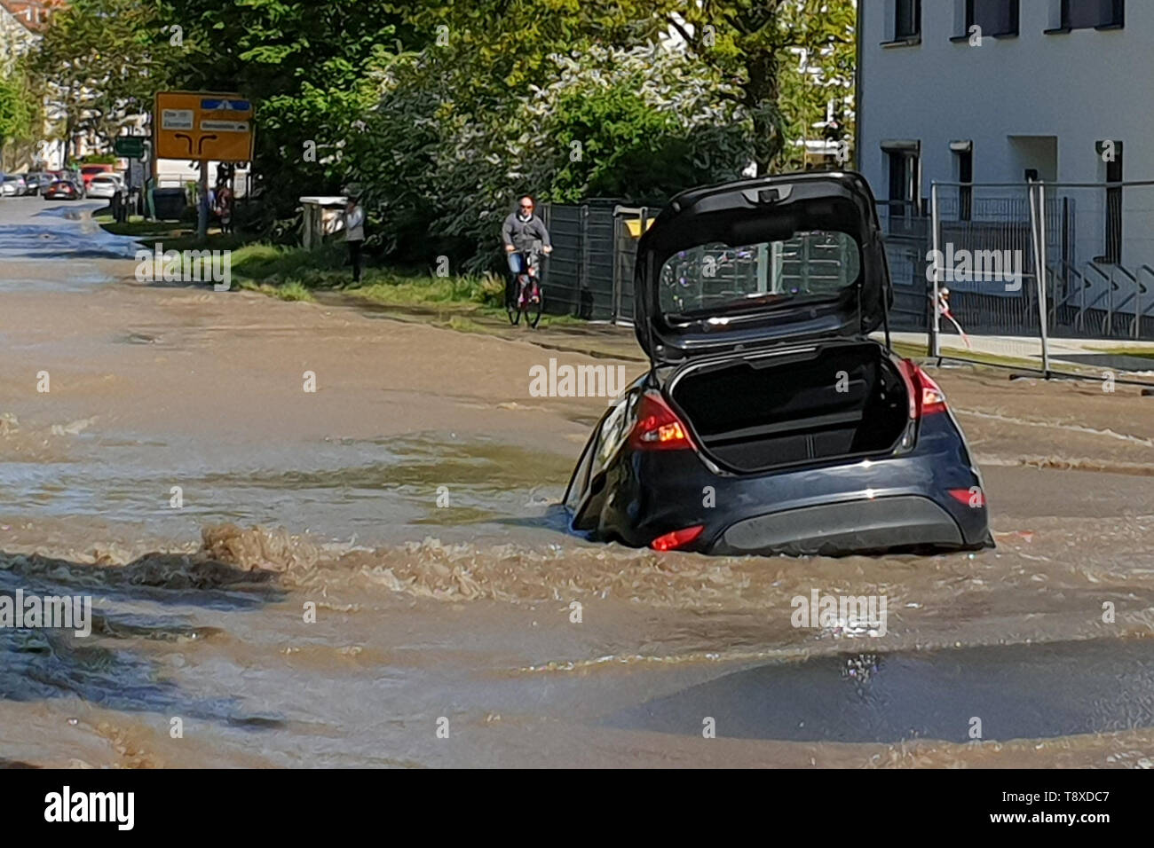 Rostock, Germany. 15th May, 2019. A car is stuck in a hole in a road after  a burst water pipe. Due to a burst water pipe on Wednesday in the east of