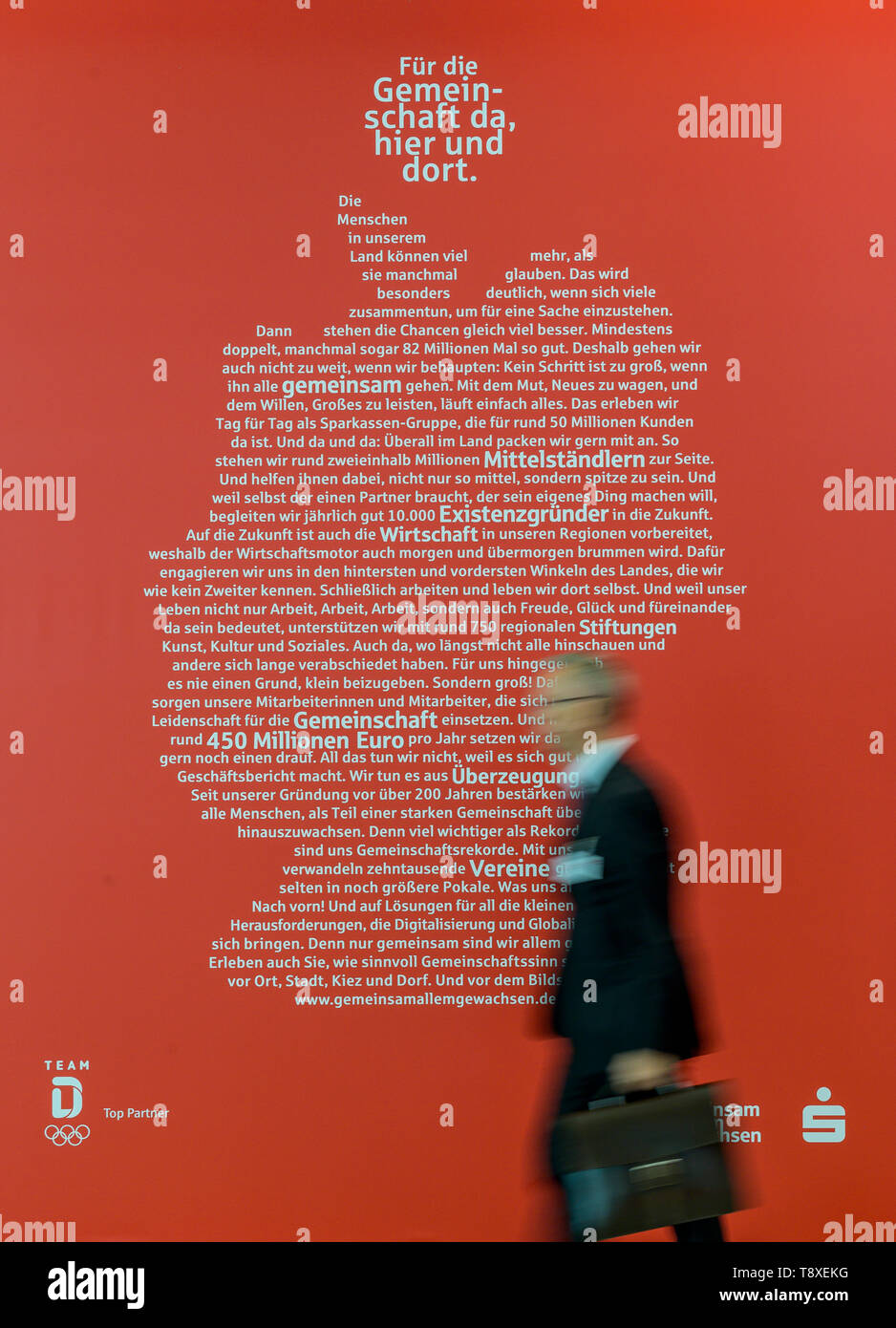 Hamburg, Germany. 15th May, 2019. A visitor of the 26th German Savings Banks Day walks along the Sparkasse in front of an advertising poster showing the outline of the map of Germany. Credit: Axel Heimken/dpa/Alamy Live News Stock Photo