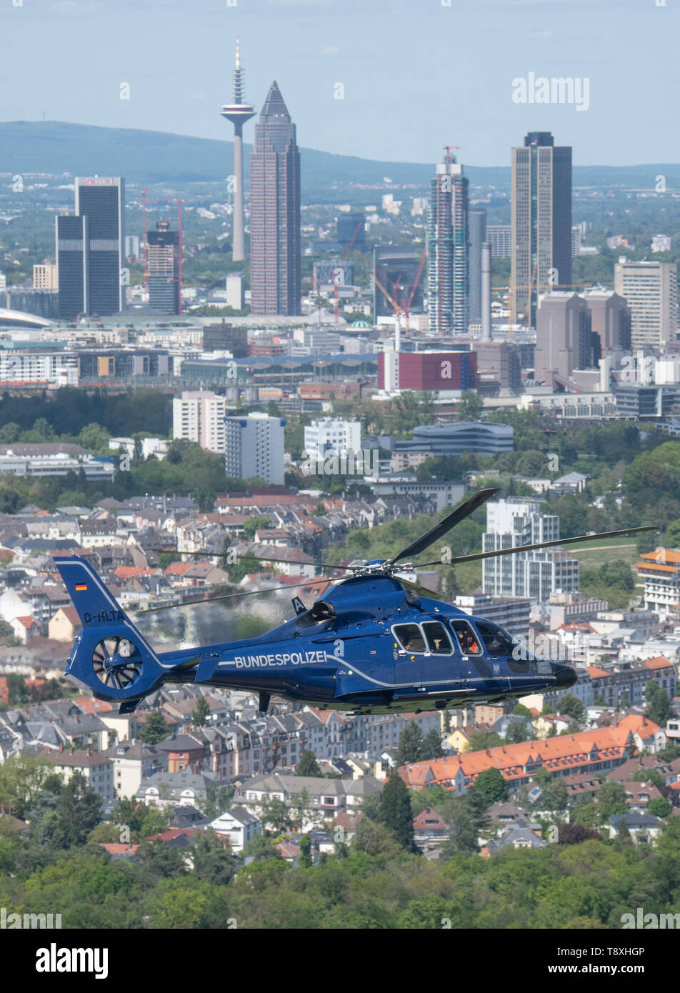 15 May 2019, Hessen, Frankfurt/Main: A Eurocopter EC 155 helicopter of the German Federal Police flies by in front of Frankfurt's bank skyline. The helicopters are ready for action within a very short time and can be used to prosecute perpetrators on the ground, to relocate special units or to monitor railway lines and airports. Photo: Boris Roessler/dpa Stock Photo