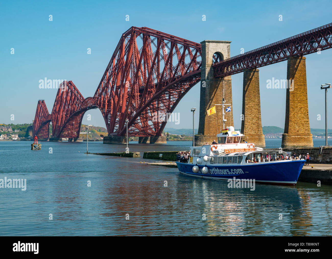 South Queensferry, Scotland, United Kingdom, 15 May 2019. UK Weather: A sunny warm day on the Firth of Forth coast at the iconic Forth Rail Bridge and a tourist boat loading passengers Stock Photo