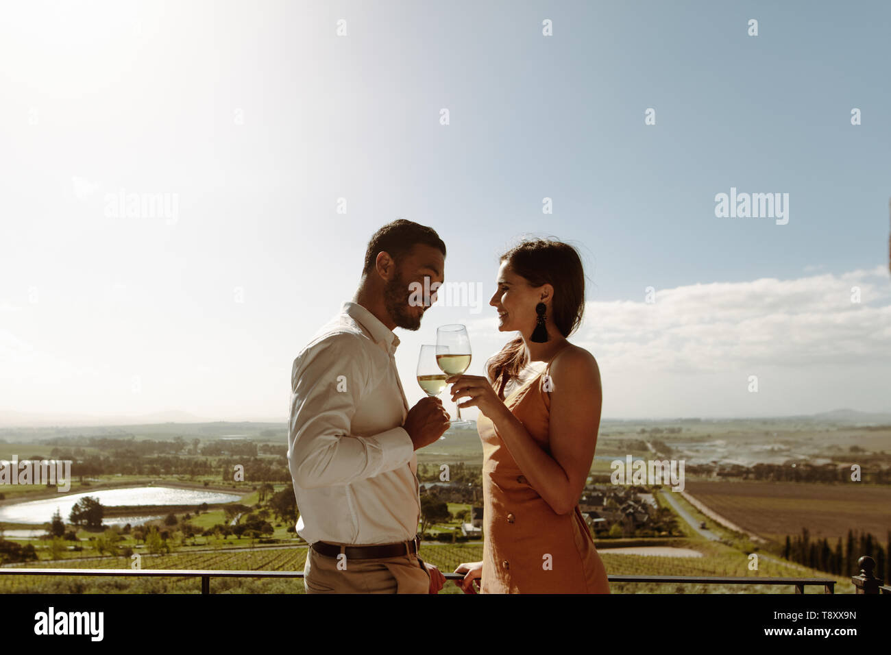 Smiling man and woman standing and talking to each other holding a ...