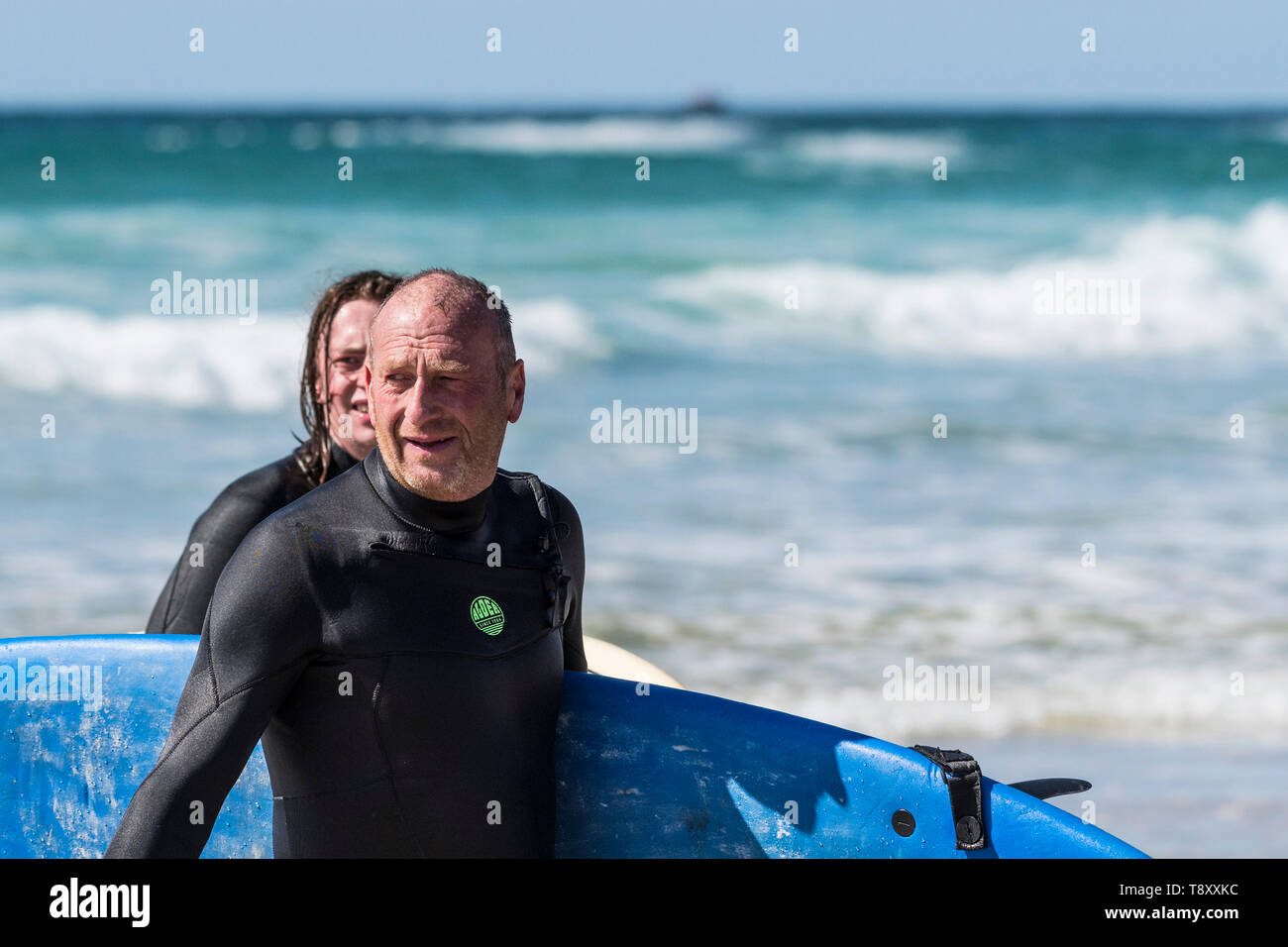 Surfers walking out of the sea at Fistral in Newquay in Cornwall. Stock Photo