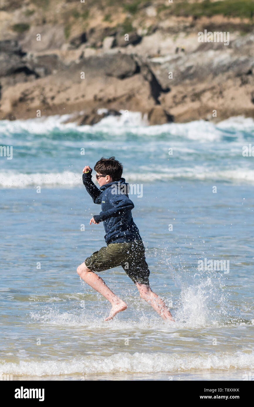An excited teenage holidaymaker running into the sea at Fistral in Newquay in Cornwall. Stock Photo