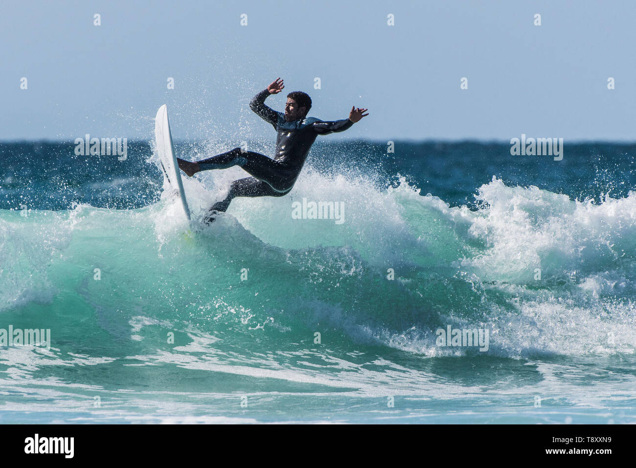 Spectacular surfing action as a surfer rides a wave in a jade coloured sea at Fistral in Newquay in Cornwall. Stock Photo