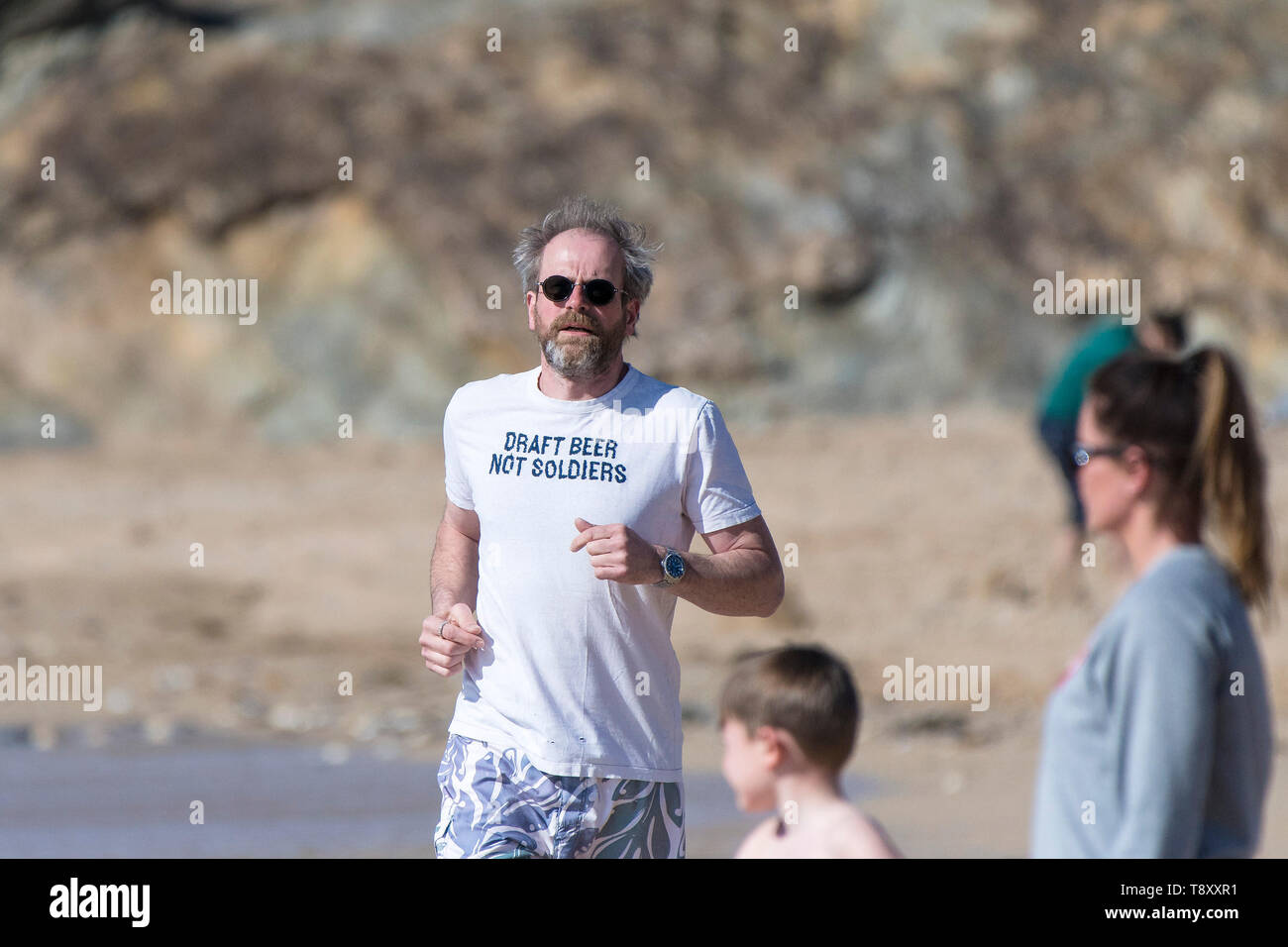 A mature man wearing a t shirt with an amusing slogan jogging along the shoreline on Fistral Beach in Newquay in Cornwall. Stock Photo