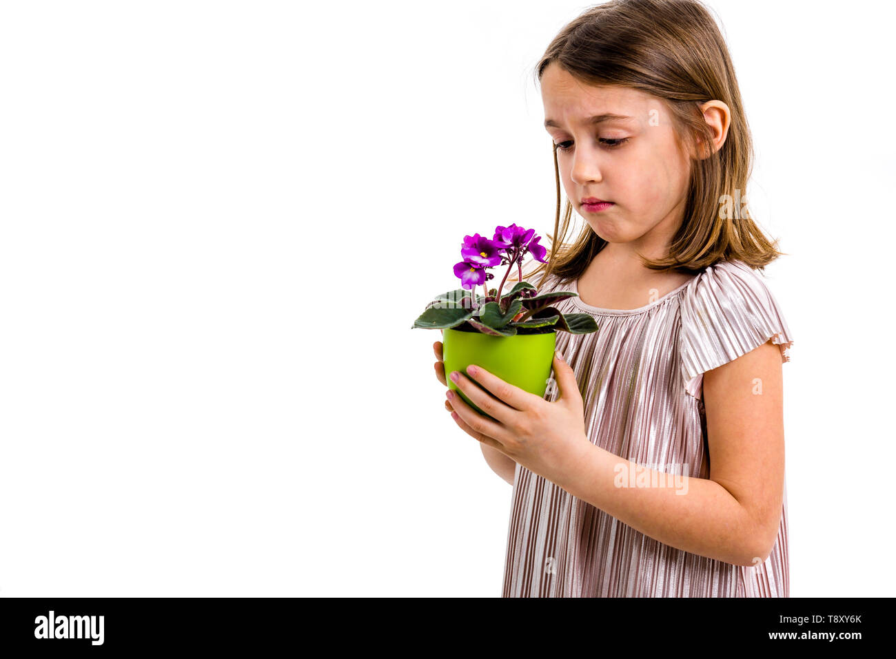 Sad young little girl holding flower pot mourning family loss. Child grieving over losing loved ones. Girl looking at flower pot, sad face, crying. Pr Stock Photo