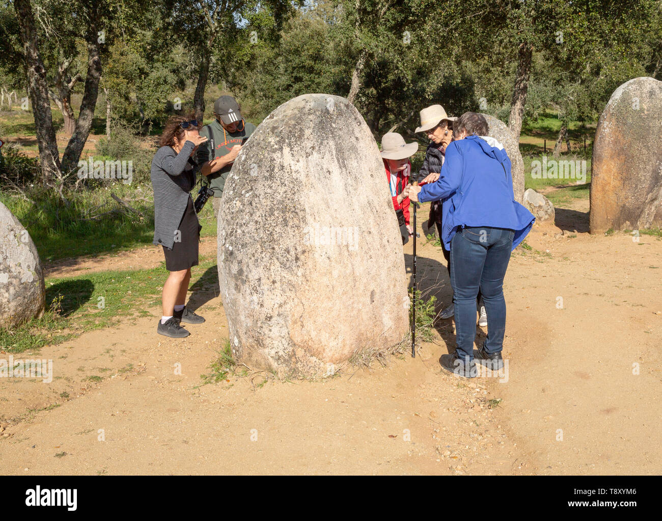 Tourists standing stones looking for feint carved markings, Neolothic