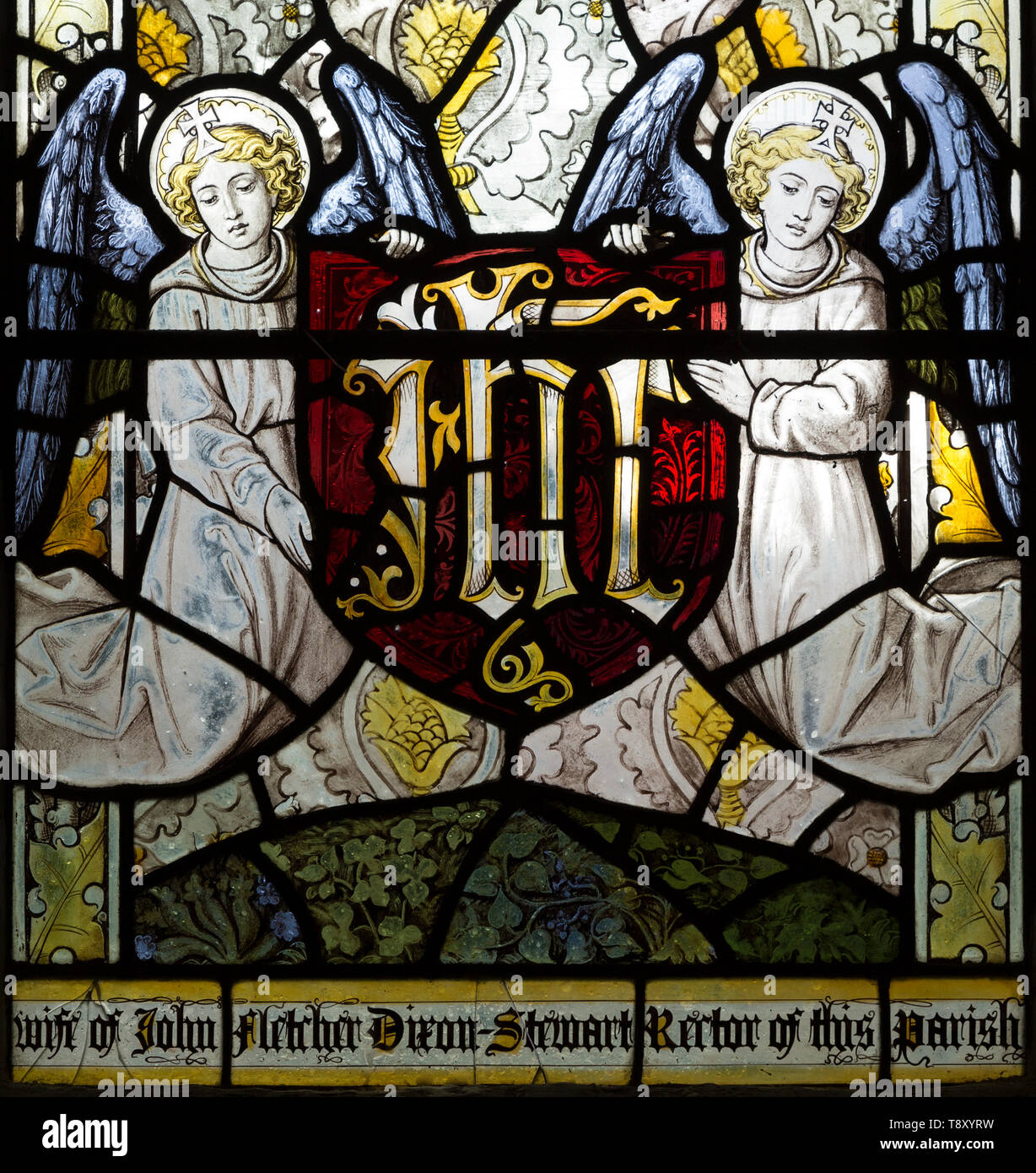 Angels holding shield with IHS motif stained glass window by Burlisson and Grylls 1906, Stanton St Bernard, Wiltshire, England, UK Stock Photo