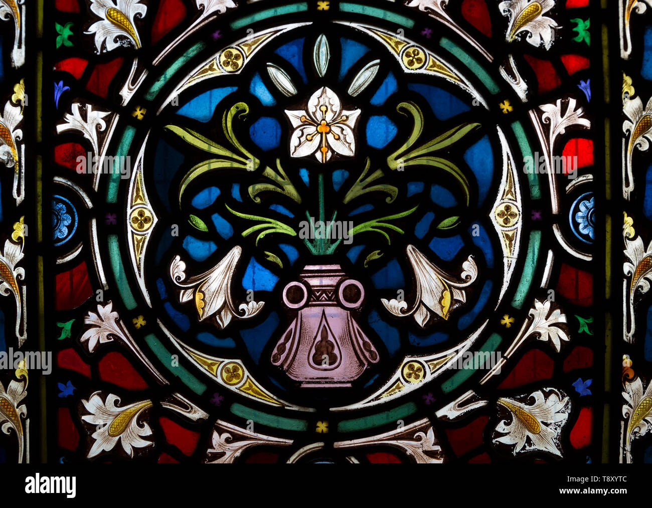 Ornamental stained glass window lily flowers and floral decoration, All Saints church, Stanton St Bernard, Wiltshire, England, UK  Lavers and Barraud Stock Photo