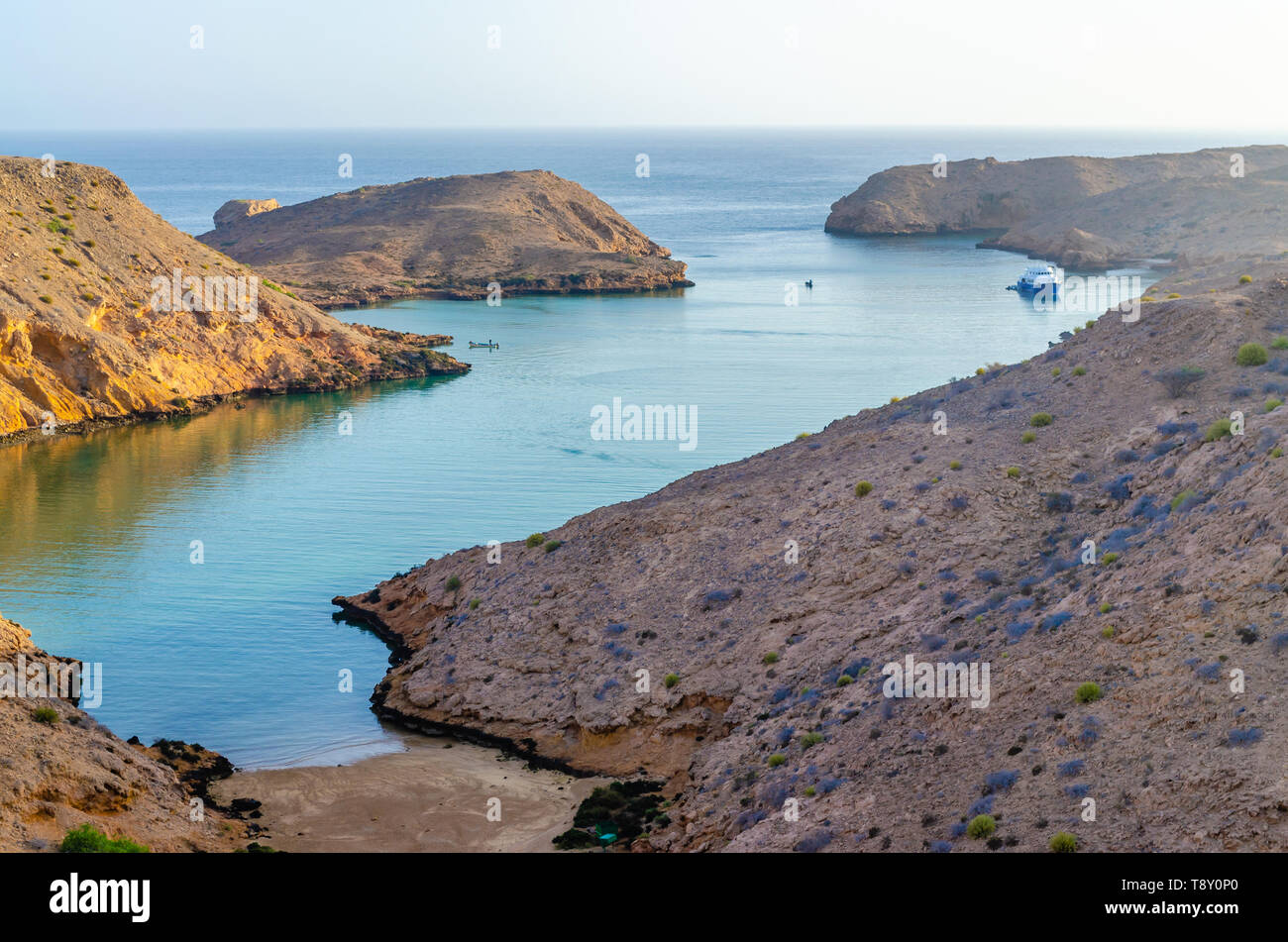 Typical Omani Landscape with brown soiled hills and a creek from the sea with turquoise water. Stock Photo