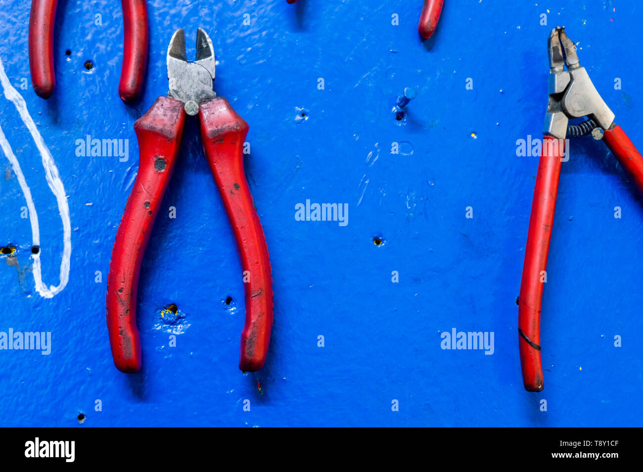 Diagonal pliers on a  blue painted wooden board in a factory storage room. Stock Photo