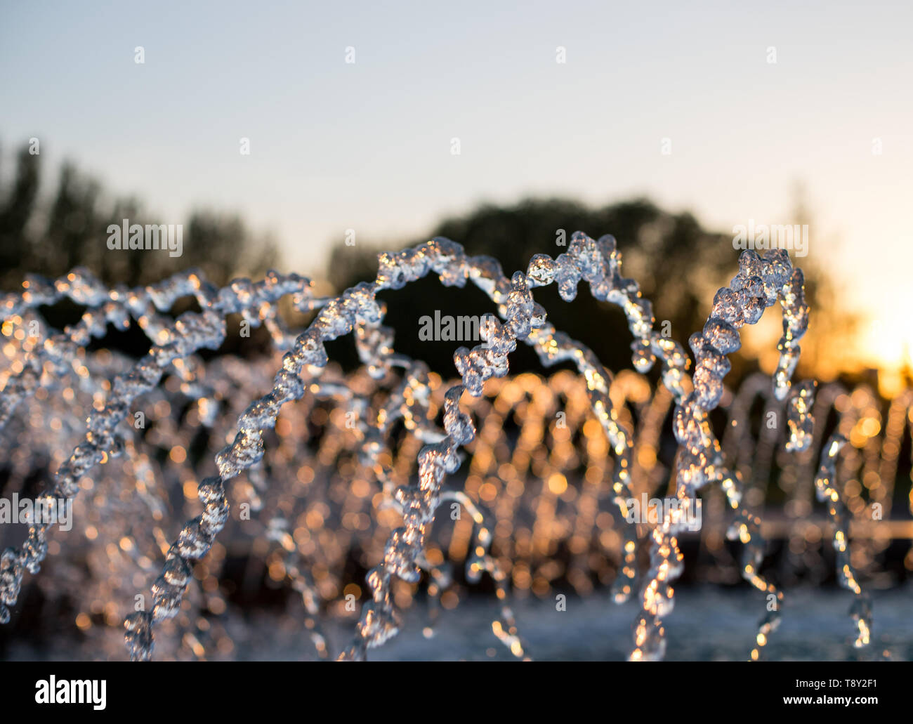 Jets of water in the fountain on a blurred background. Fountain closeup at sunset Stock Photo