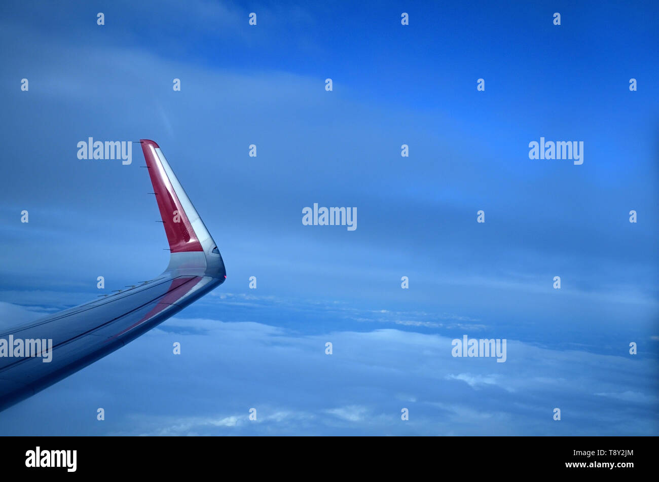 Wing of airplane in blue mid sky is captured through window Stock Photo ...