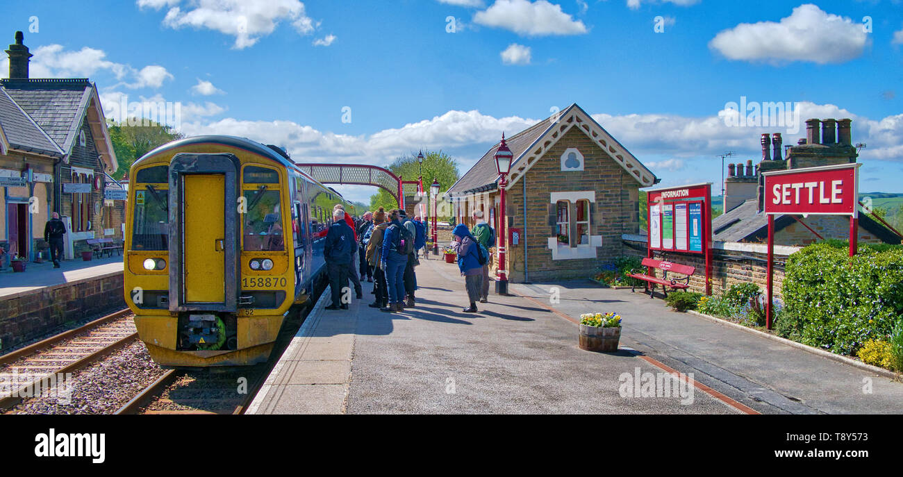 Tourists at Settle Station wait to board the train to Carlisle, set to cross the famous Ribblehead Viaduct along their way Stock Photo