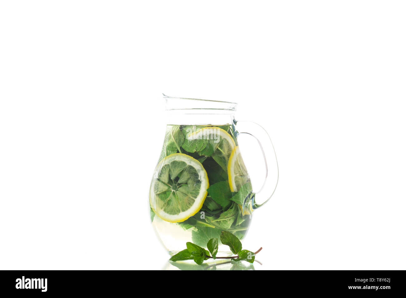 Fresh cold lemonade with lemons and mint in a carafe isolated on white Stock Photo