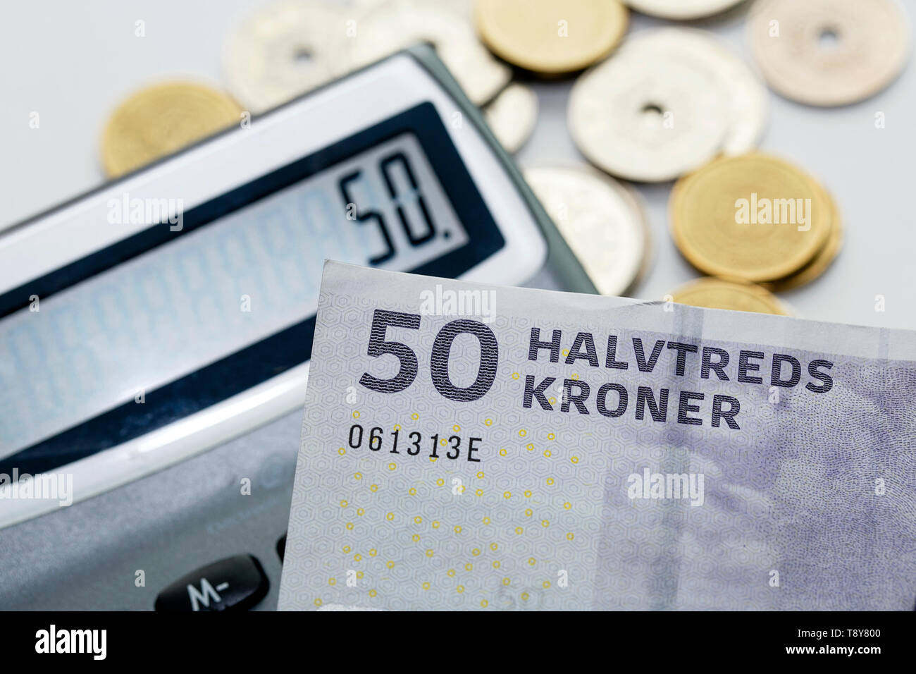 A fifty krone note over a calculator and mixed coins with selective