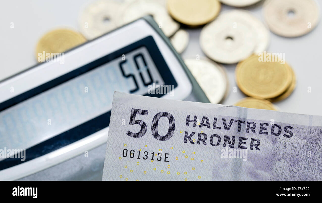 A fifty krone note over a calculator and mixed coins with selective