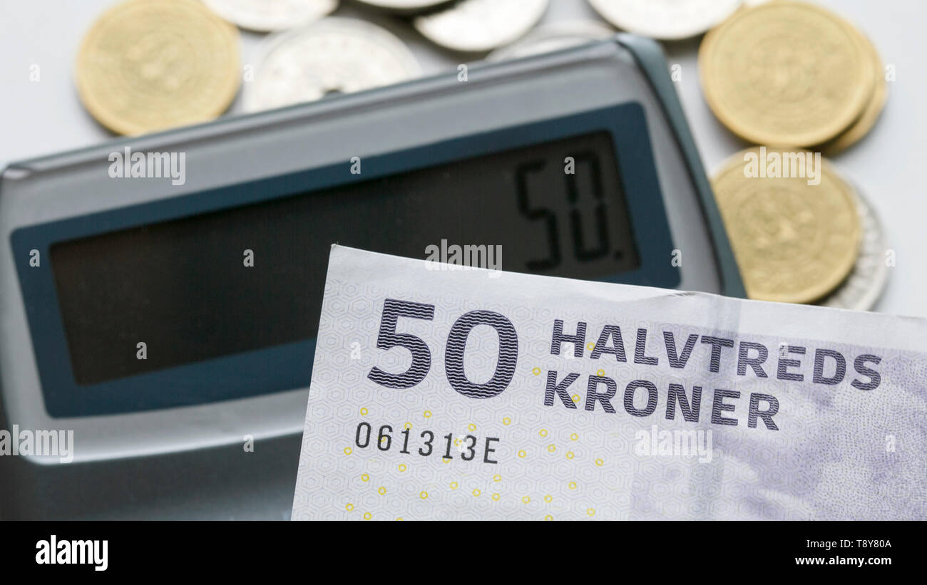 A fifty krone note over a calculator and mixed coins with selective