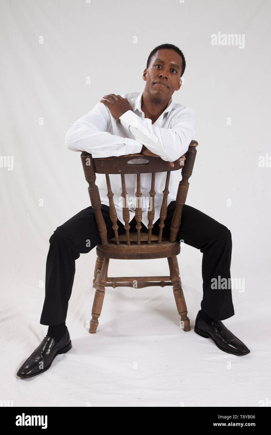 Handsome black man sitting backwards in a chair Stock Photo Alamy