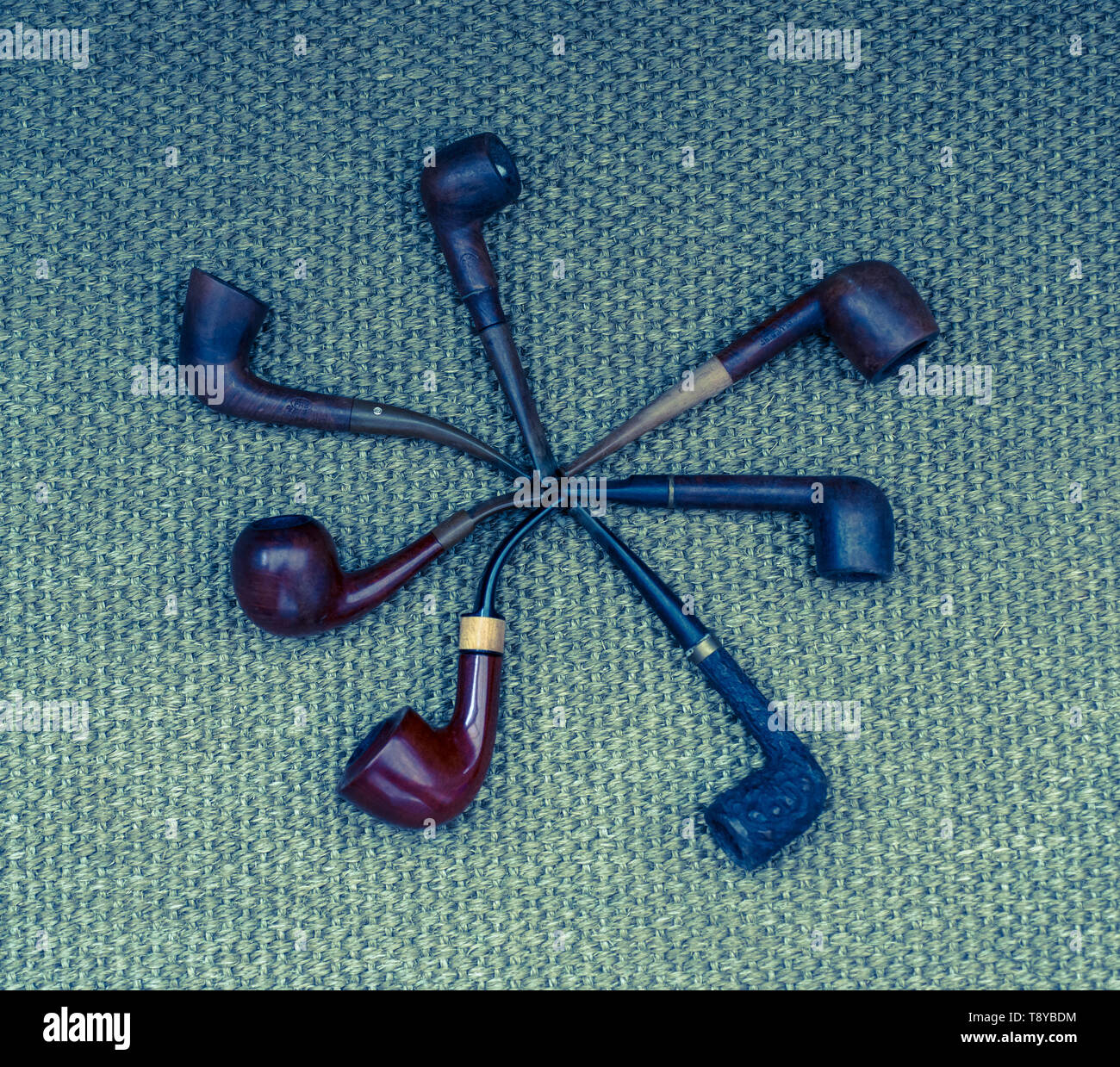 Different tobacco smoking pipes laid on a mesh background Stock Photo