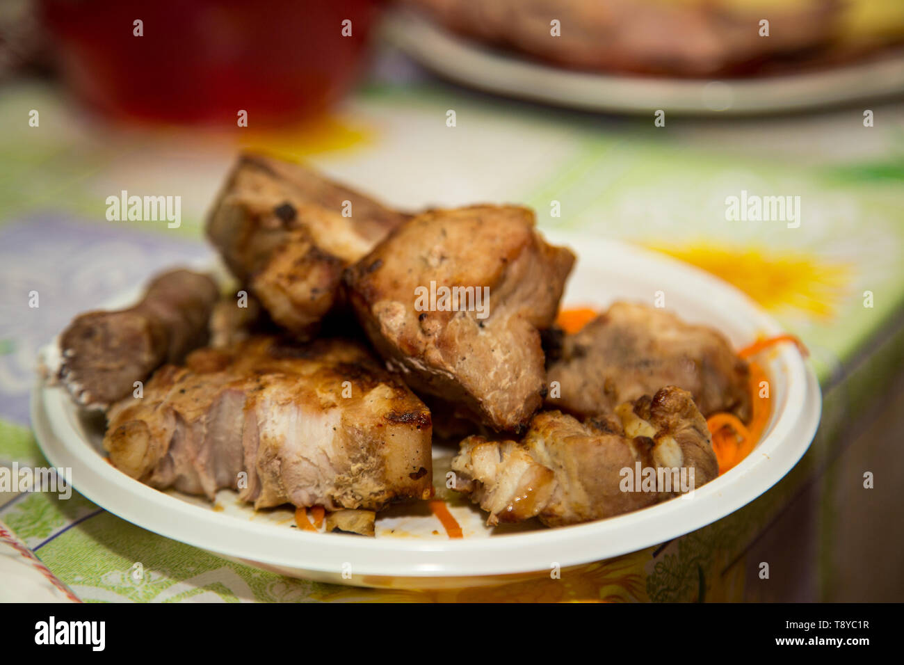 Pieces of roasted meat on the coals lie on the festive table. Stock Photo